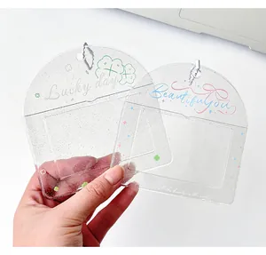 Dettaglio di porta fotocarte trasparenti glitterati con quadrifoglio e fiocco su bianco
