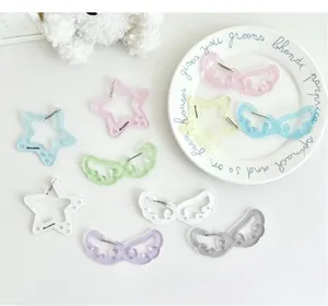 Primer plano de dijes de acrílico con purpurina en forma de estrella y ala con mosquetón