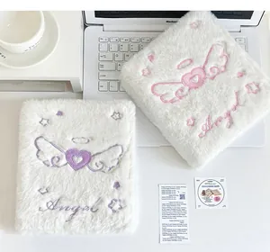 Detalle de carpetas de felpa blanca con bordado de alas de corazón de ángel y escritura
