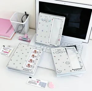 Tre album Kpop con illustrazioni di gatti e stelle sopra un computer portatile