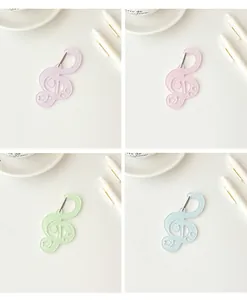 Detalle de colgantes de clave de sol en acrílico con colores pastel para bolsos