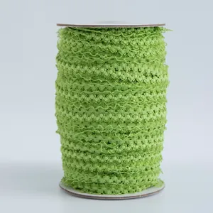 Macro di nastro elastico verde erba da 1,5 cm con mini pompon su rotolo di cartone