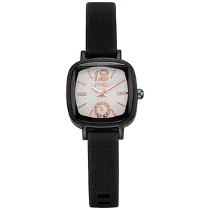 Détail de montre carrée noire avec bracelet silicone, aiguilles or rose et diamants
