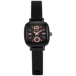 Gros plan de la montre carrée noire avec aiguilles en or rose et bracelet en silicone