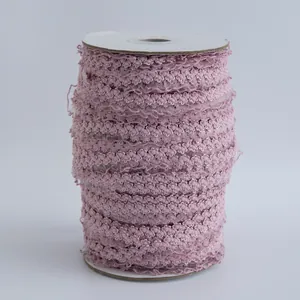 Vista macro dettagliata del nastro elastico a pizzo rosa con trama fine e bordo ondulato