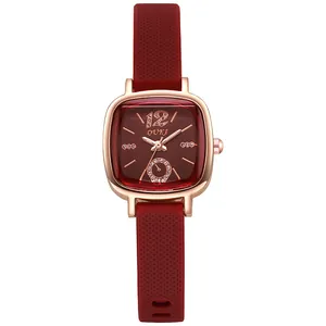 Détail du boîtier carré or rose et bracelet en silicone bordeaux avec des strass