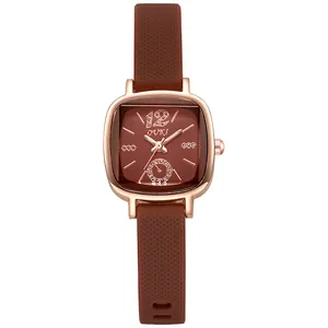 Détail du cadran carré en or rose avec strass et bracelet en silicone marron