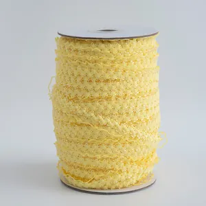 Dettaglio di pizzo elastico giallo da 1,5 cm avvolto in un rotolo per cucito e fai da te