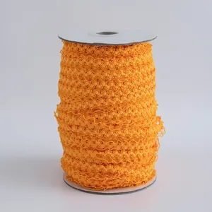 Dettaglio di passamaneria con pompon arancione da 1,5cm avvolta su rocchetto