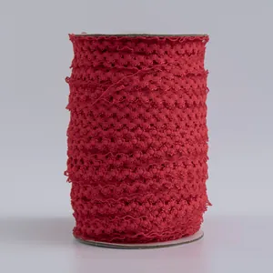 Dettaglio di nastro in pizzo elastico rosso scuro da 1,5 cm avvolto su un nucleo