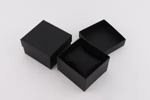 Detalle de caja de regalo negra cuadrada para reloj con tapa texturizada y cojín