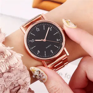 Detalle de reloj de cuarzo oro rosa con esfera negra y números en la muñeca femenina