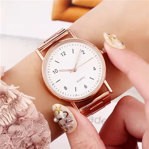 Primer plano de elegante reloj de cuarzo oro rosa con correa de acero en muñeca mujer