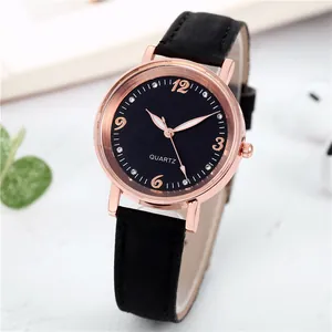 Detail of rose gold quartz watch with rhinestone markers and black leather strap