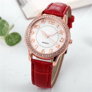 Detail einer roségoldenen Quarzuhr mit Strass-Lünette und rotem Lederarmband