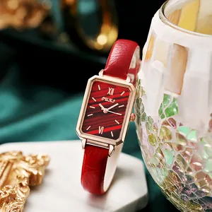 Macro detail of red rectangular quartz watch with leather strap on silk background