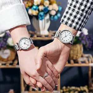 Close-up of couple holding hands wearing matching silver steel quartz watches with white dials