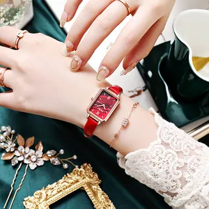 Close-up of a vintage rectangular gold watch with a red leather strap and roman dial