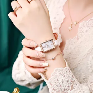 Detail view of a vintage square quartz watch with white leather strap on a model's wrist