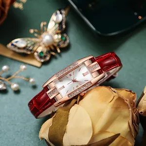 Detailed close-up of a rectangular rose gold watch with crystal bezel and red leather strap