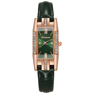 Detail of rose gold rectangular watch case with crystals and sunray green dial