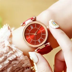 Détail d'une montre à cadran rouge soleil avec chiffres romains et boîtier or rose