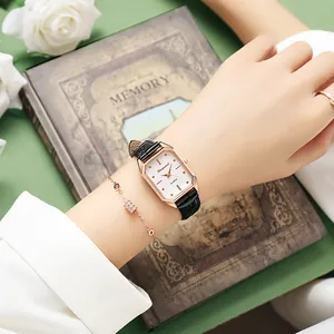 Détail macro d'une montre à quartz rectangulaire en or rose avec bracelet cuir noir