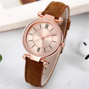 Détail de montre femme or rose avec cadran soleil et bracelet cuir à surpiqûres