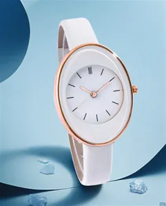 Detail of rose gold oval watch case with white leather strap and minimalist dial