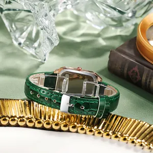 Vue détaillée du bracelet en cuir vert émeraude et montre rectangulaire en or rose sur soie