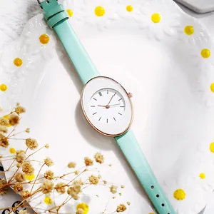 Detail of mint green leather strap and oval rose gold quartz watch on a decorative plate