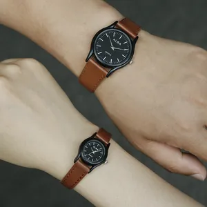 Detalle de relojes de pareja con correas de cuero marrón y esferas de cuarzo negro mate