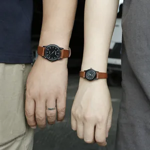 Primer plano de una pareja con relojes de cuarzo negros y correas de cuero marrón