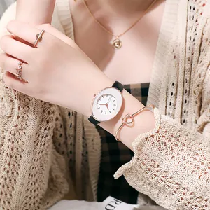 Close-up of elegant oval quartz watch with black leather strap and gold jewelry styling