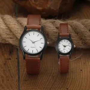 Primer plano de relojes de pareja minimalistas con correas de cuero marrón y dial blanco
