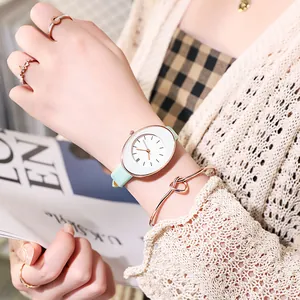 Detail of rose gold oval quartz watch with mint green leather strap on female wrist