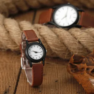 Vista de detalle de relojes de cuarzo para pareja con correa de cuero marrón sobre madera
