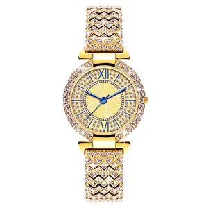 Close-up of gold-tone luxury watch showing crystal-set bezel and blue hands on radial dial