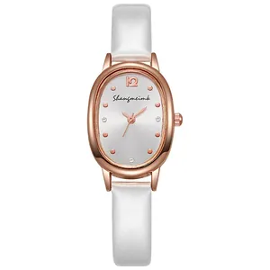 Nahaufnahme einer roségoldenen ovalen Quartzuhr mit weißem Lederarmband und Zifferblatt