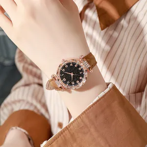 Dettaglio dell'orologio in oro rosa con strass, cinturino in pelle marrone e quadrante nero
