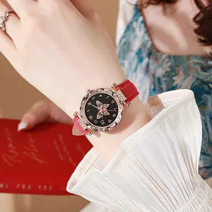 Detalle de reloj en oro rosa con esfera de mariposa y correa roja esmerilada