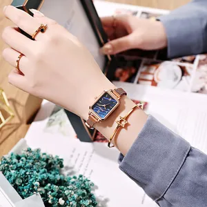 Detail of rose gold square watch with blue dial and matching starry jewelry set
