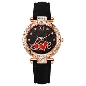 Détail de montre en or rose avec strass, cadran noir étoilé et inscription Love