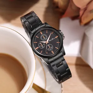 Détail d'une montre en acier noir avec cadran or rose à côté d'une tasse à café