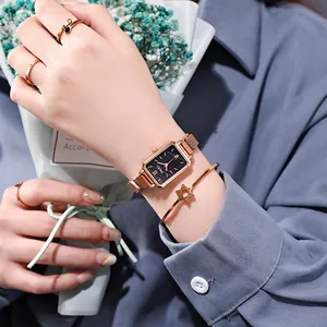 Detail of rose gold rectangular watch with black dial and matching star charm bracelet