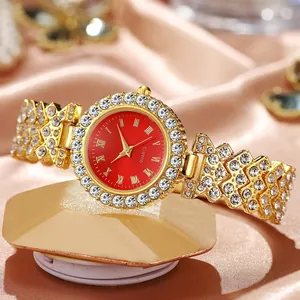 Detalle de reloj de cuarzo dorado con esfera roja y correa incrustada con circonitas