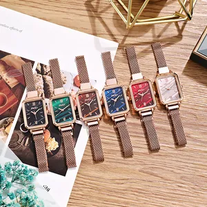Detail view of colorful vintage square watches with elegant mesh straps on a desk