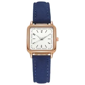 Detalle de reloj cuadrado de oro rosa con correa de cuero azul oscuro y esfera blanca