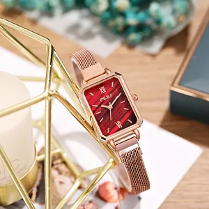 Detail of rose gold rectangular watch with red dial and magnetic mesh strap on decor