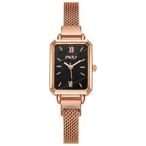 Macro detail of rectangle quartz watch with black textured dial and rose gold mesh strap